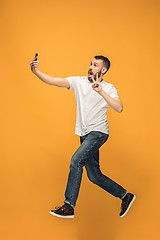 Image showing Time to take selfie. Full length of handsome young man taking selfie while jumping