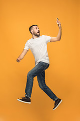 Image showing Full length of handsome young man taking selfie while jumping