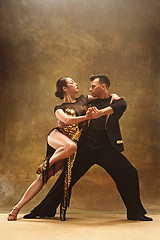 Image showing Dance ballroom couple in gold dress dancing on studio background.