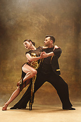 Image showing Dance ballroom couple in gold dress dancing on studio background.