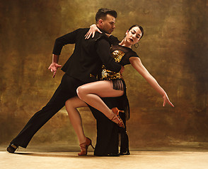 Image showing Dance ballroom couple in gold dress dancing on studio background.