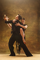 Image showing Dance ballroom couple in gold dress dancing on studio background.