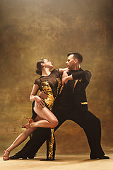 Image showing Dance ballroom couple in gold dress dancing on studio background.