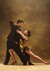 Image showing Dance ballroom couple in gold dress dancing on studio background.