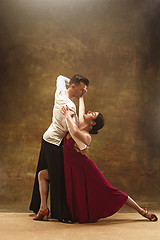 Image showing Dance ballroom couple in red dress dancing on studio background.