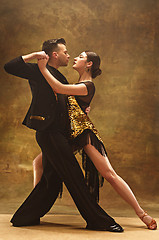 Image showing Dance ballroom couple in gold dress dancing on studio background.