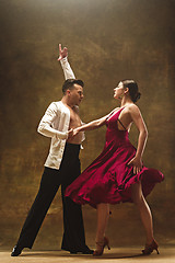 Image showing Dance ballroom couple in red dress dancing on studio background.