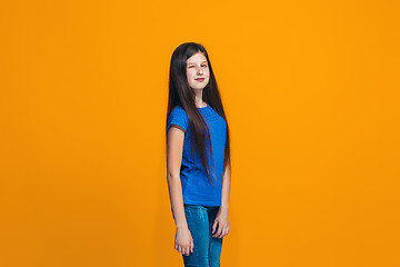 Image showing The happy teen girl standing and smiling against orange background.