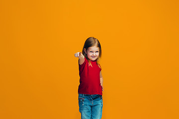 Image showing The happy teen girl pointing to you, half length closeup portrait on orange background.