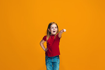 Image showing The happy teen girl pointing to you, half length closeup portrait on orange background.