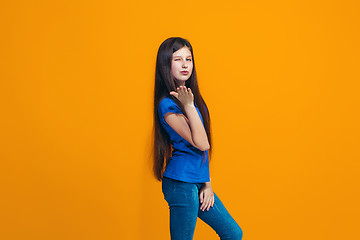 Image showing The happy teen girl standing and smiling against orange background.