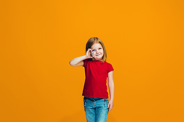 Image showing The happy teen girl standing and smiling against orange background.