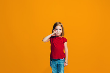 Image showing The happy teen girl standing and smiling against orange background.