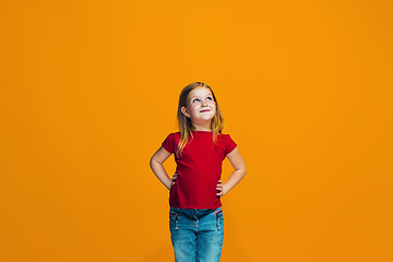 Image showing The happy teen girl standing and smiling against orange background.