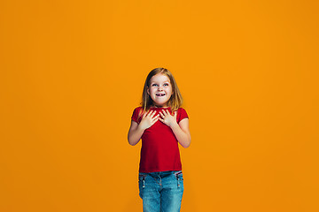 Image showing The happy teen girl standing and smiling against orange background.