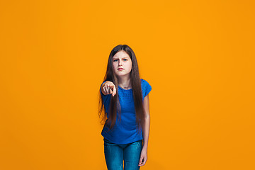 Image showing The happy teen girl pointing to you, half length closeup portrait on orange background.