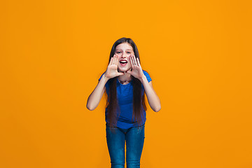 Image showing Isolated on yellow young casual teen girl shouting at studio