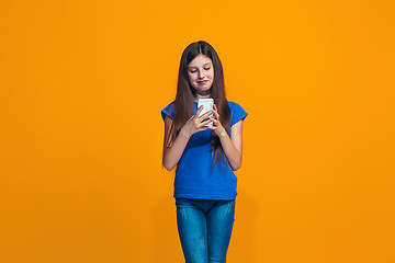Image showing The happy teen girl standing and smiling against orange background.