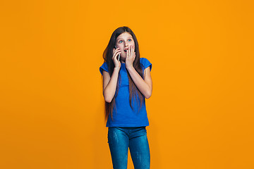 Image showing The happy teen girl standing and smiling against orange background.