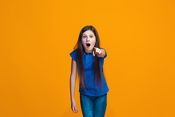 Image showing The happy teen girl pointing to you, half length closeup portrait on orange background.