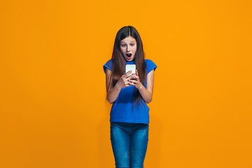 Image showing The happy teen girl standing and smiling against orange background.