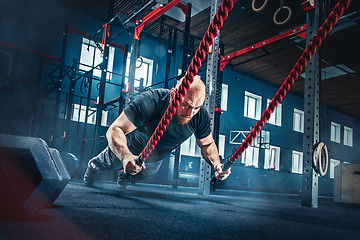 Image showing Men with battle rope battle ropes exercise in the fitness gym.