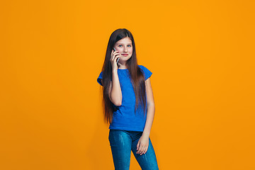 Image showing The happy teen girl standing and smiling against orange background.