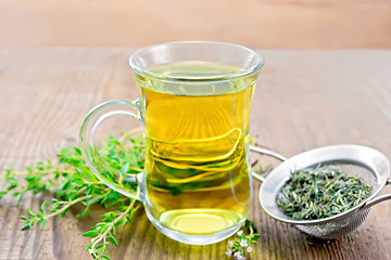 Image showing Tea of thyme in mug with strainer on wooden board