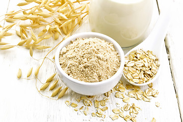 Image showing Flour oat in bowl with milk on white wooden board