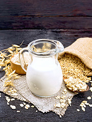 Image showing Milk oatmeal in jug on dark wooden board