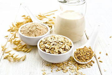 Image showing Oat flakes with flour and milk on white wooden board