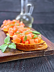 Image showing Bruschetta with tomato and basil on black wooden board