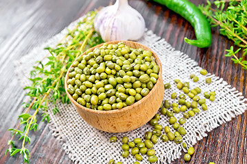 Image showing Mung beans in wooden bowl with thyme and pepper on dark board