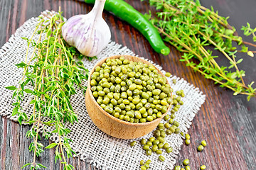 Image showing Mung beans in wooden bowl with thyme and pepper on board