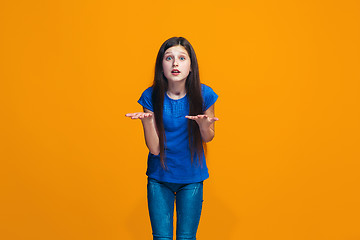 Image showing Beautiful female half-length portrait on orange studio backgroud. The young emotional teen girl