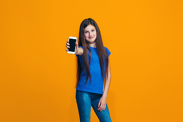 Image showing The happy teen girl standing and smiling against orange background.