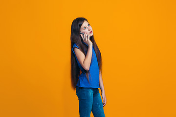 Image showing The happy teen girl standing and smiling against orange background.