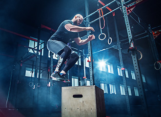 Image showing Man jumping during exercises in the fitness gym. CrossFit.