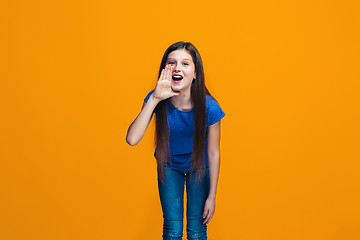 Image showing Isolated on yellow young casual teen girl shouting at studio