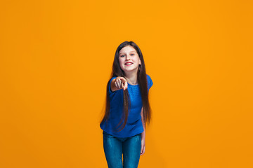 Image showing The happy teen girl pointing to you, half length closeup portrait on orange background.