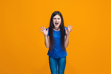 Image showing Portrait of angry teen girl on a orange studio background