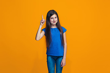 Image showing The happy teen girl standing and smiling against orange background.