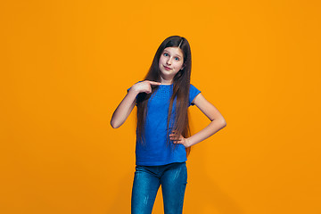 Image showing The happy teen girl standing and smiling against orange background.