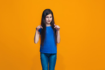 Image showing The happy teen girl standing and smiling against orange background.