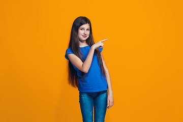 Image showing The happy teen girl standing and smiling against orange background.