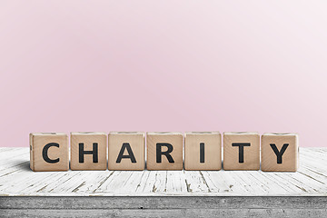 Image showing Charity sign on a wooden desk with a pink wall