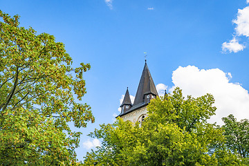 Image showing Fairytale castle tower rising up behind green trees