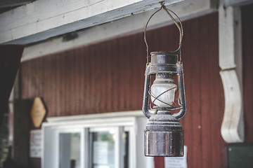 Image showing Old oil lamp hanging on a porch outside