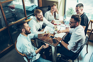 Image showing Young cheerful people smile and gesture while relaxing in pub.