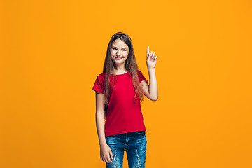 Image showing The happy teen girl standing and smiling against orange background.